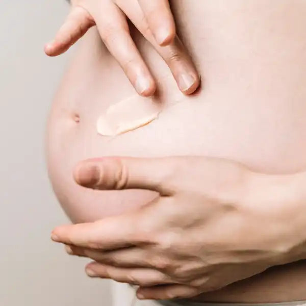 Hands applying moisturizer or cream to bare skin.